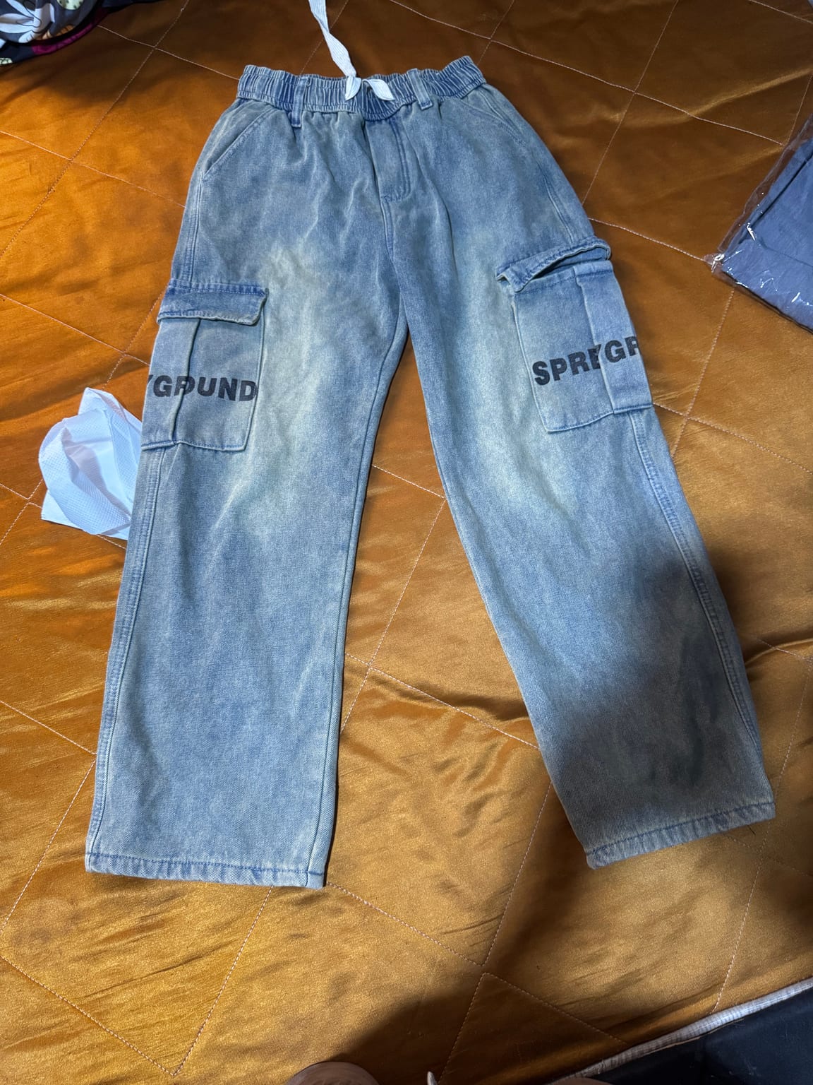 Features elastic waistband and large side pockets with text.